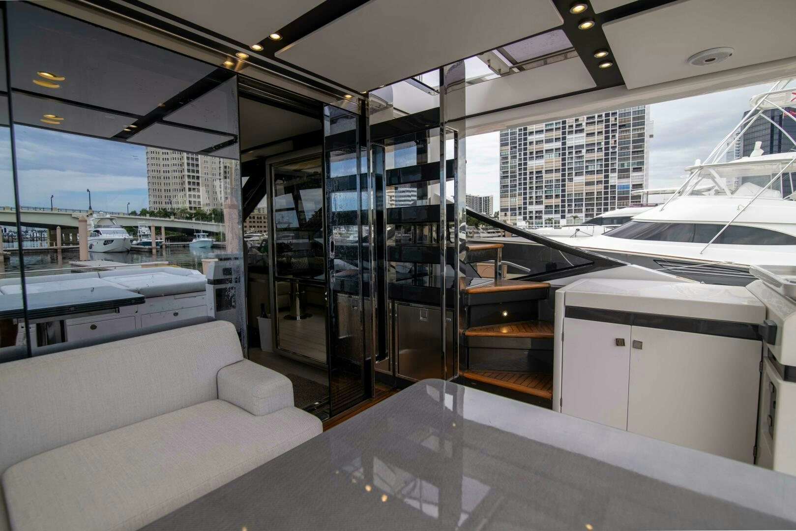 a room with glass walls and a couch and a table with a view of a city aboard TRIPLE PLAY Yacht for Sale