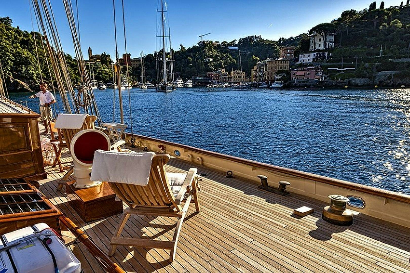 a deck with chairs and a body of water and a person standing on the side aboard INVADER Yacht for Charter