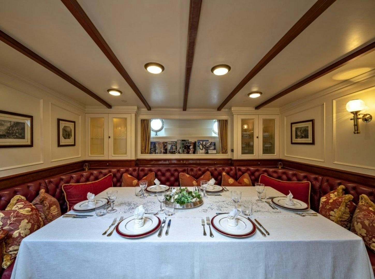 a dining table with plates and a table with a couch and a mirror aboard INVADER Yacht for Charter