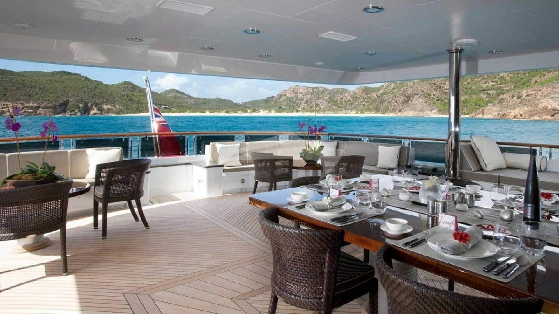 a table set for a meal on a deck overlooking a body of water aboard OCEAN CLUB Yacht for Charter