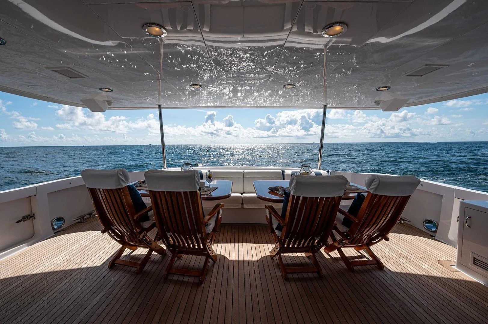 a deck with chairs and tables on it by a large body of water aboard MAGNUM RIDE Yacht for Charter