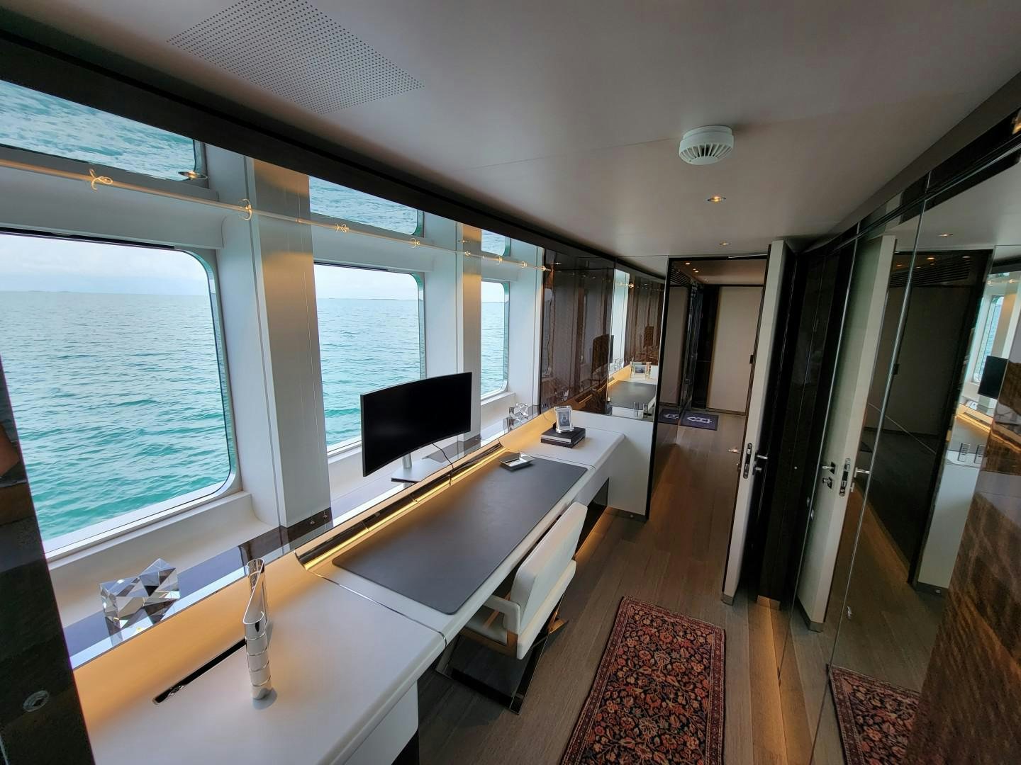 a room with a large window and a desk with a computer on it aboard KNIGHT Yacht for Charter
