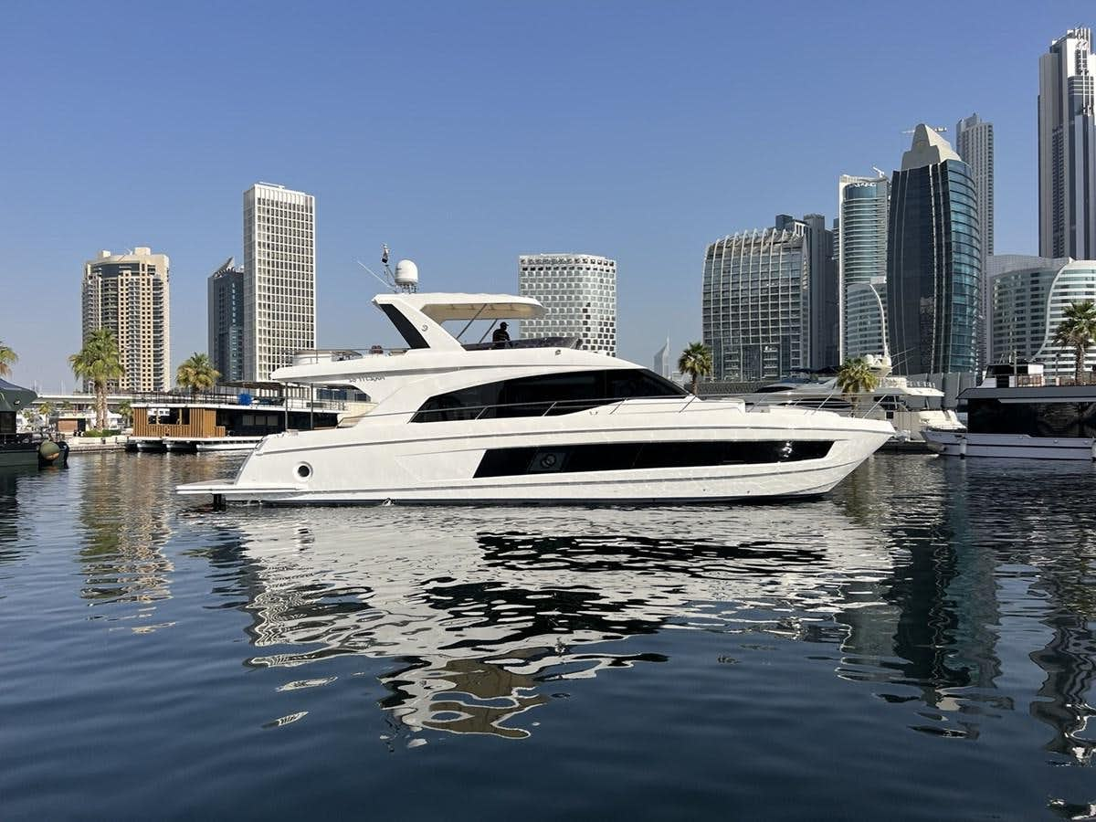 a white boat in a body of water with a city in the background aboard 2018 GULF CRAFT MAJESTY 62 Yacht for Sale