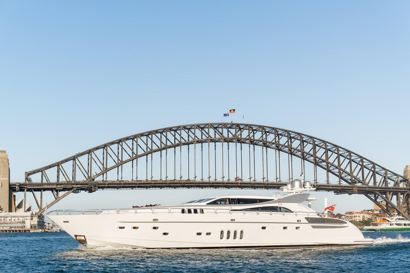 a large white boat in the water with Sydney Harbour Bridge in the background aboard YOLO Yacht for Sale