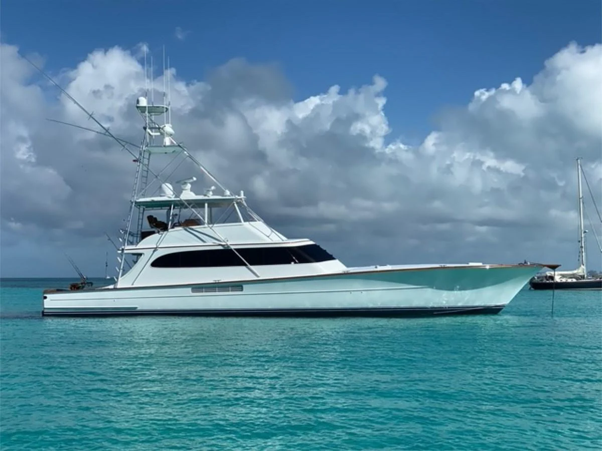 A sleek yacht is anchored in turquoise waters under a partly cloudy sky. aboard REMAIN CALM Yacht for Sale