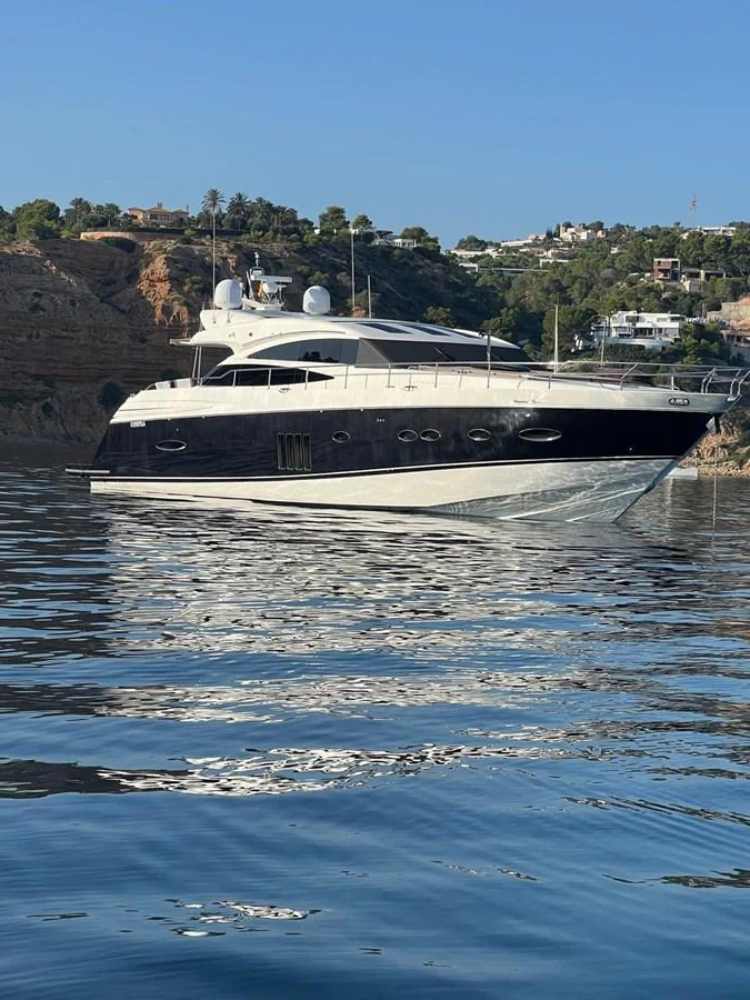 A sleek and modern yacht is anchored in a serene coastal area, reflecting beautifully on the calm water. aboard SFYFALL Yacht for Sale