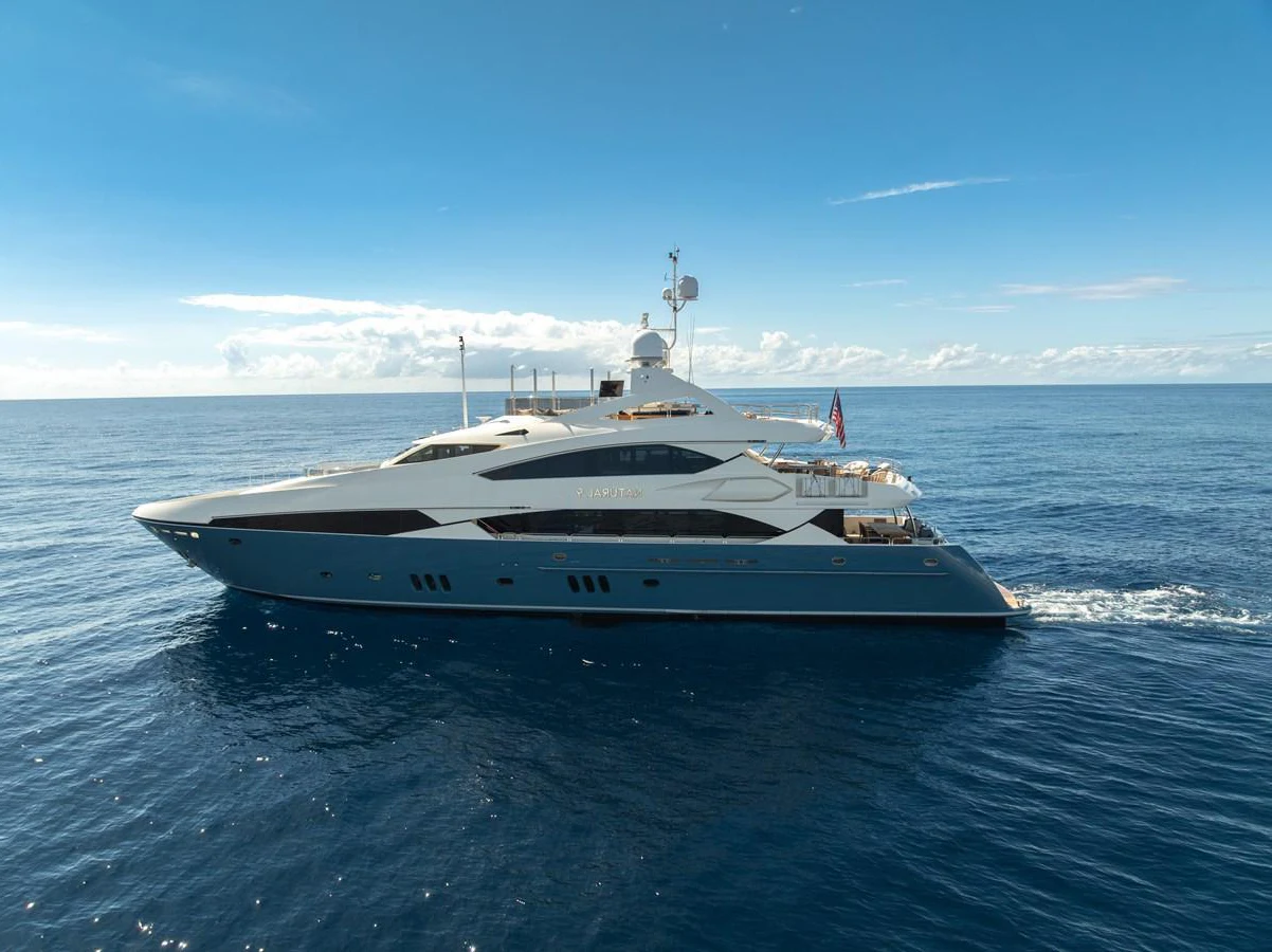 A sleek and modern yacht glides gracefully across the open sea under a clear blue sky. aboard NATURAL 9 Yacht for Sale