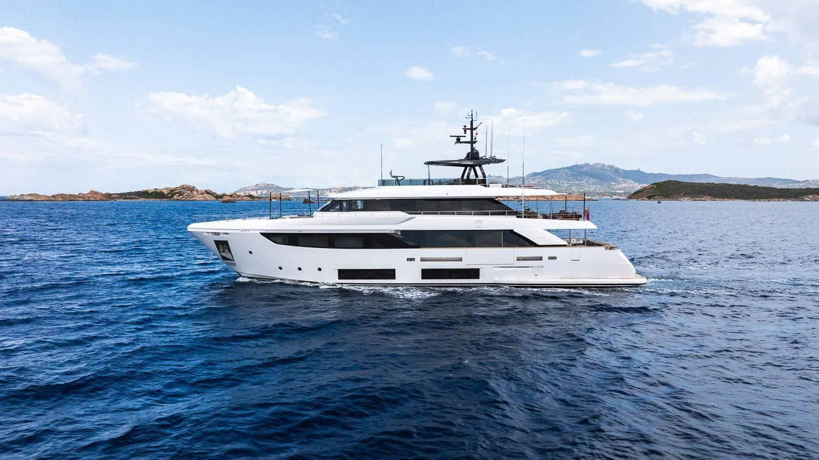 A sleek and modern yacht cruising on calm blue waters with a scenic coastline in the background. aboard QUEEN J III Yacht for Sale