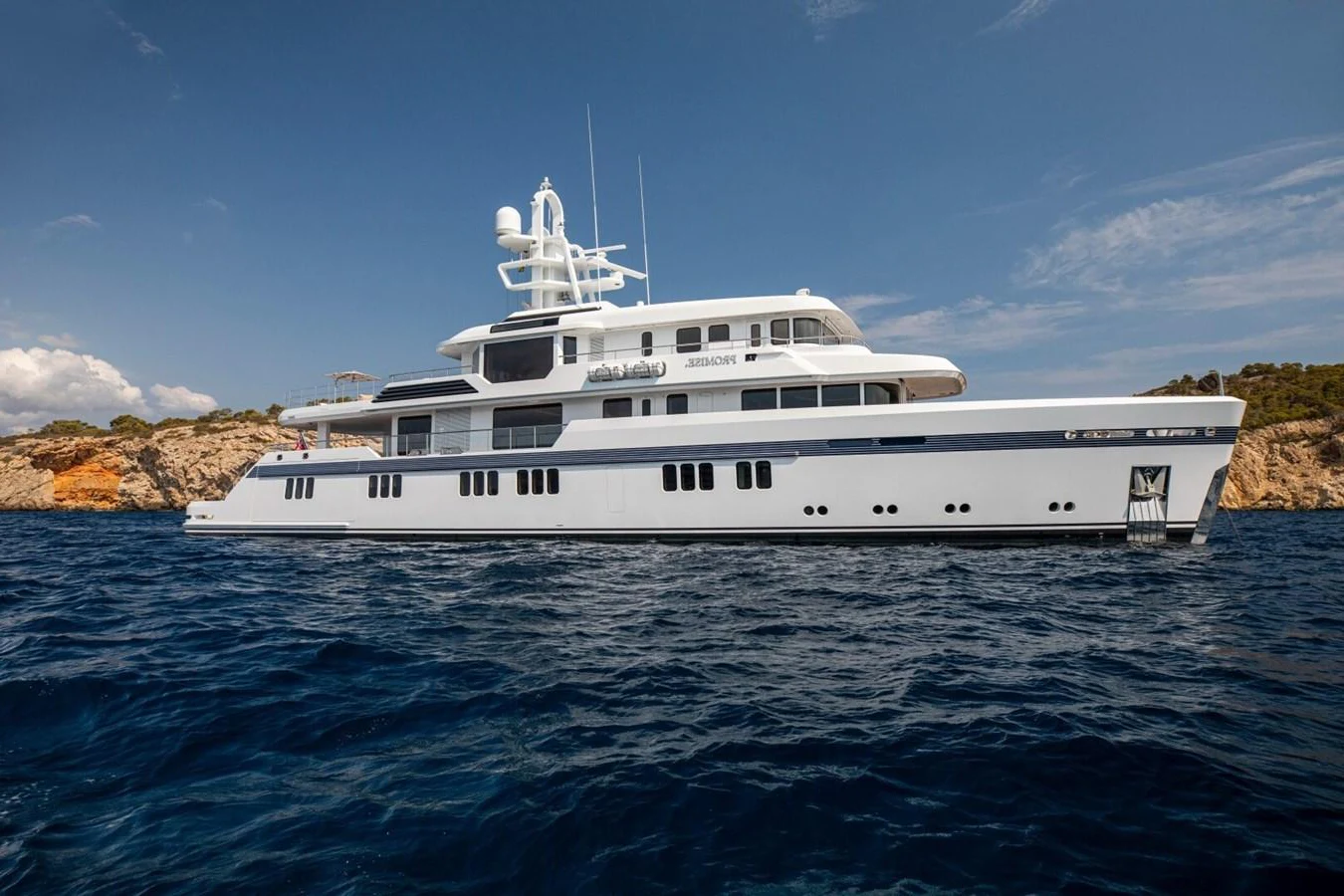 A luxurious yacht cruises gracefully on the open sea under a clear blue sky. aboard PROMISE Yacht for Sale