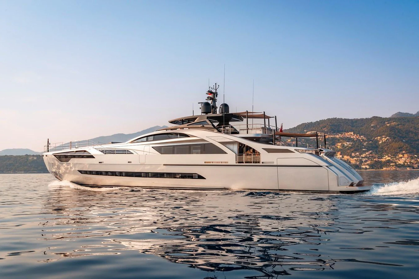 A sleek and modern yacht glides gracefully on calm waters with a scenic backdrop. aboard PERSHING 140 Yacht for Sale