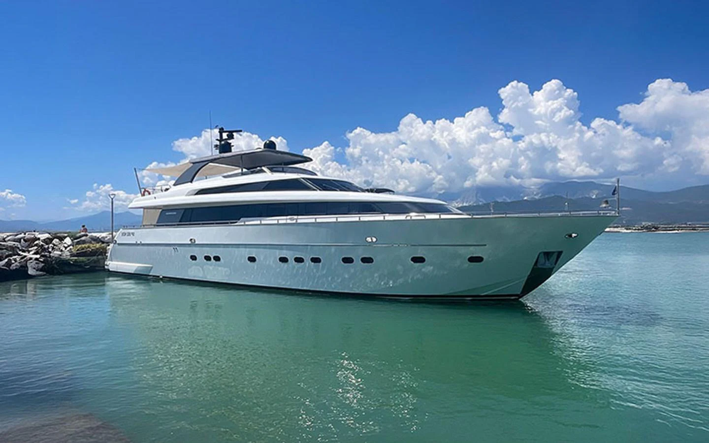 A sleek and modern yacht is docked in a serene harbor under a clear blue sky. aboard MEP TOGETHER Yacht for Sale