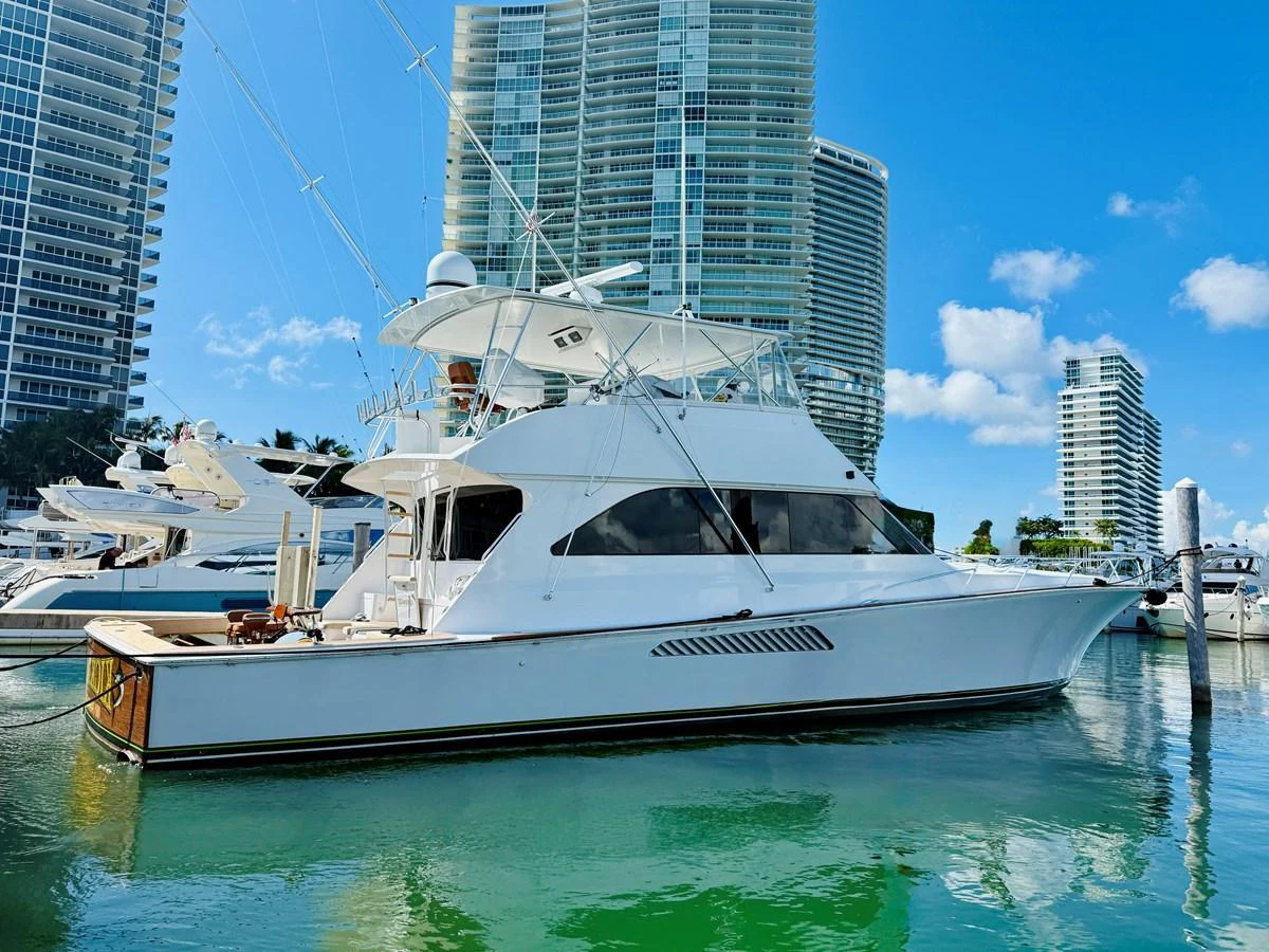 A sleek yacht is docked in a marina with modern high-rise buildings in the background. aboard KICKBACK Yacht for Sale