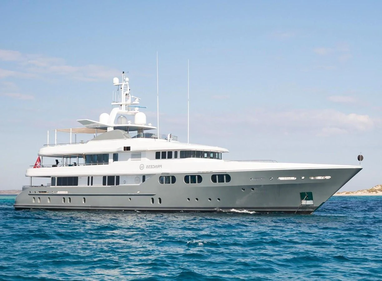 A sleek and modern yacht glides gracefully on the open water under a clear sky. aboard PRINCESS TOO Yacht for Sale