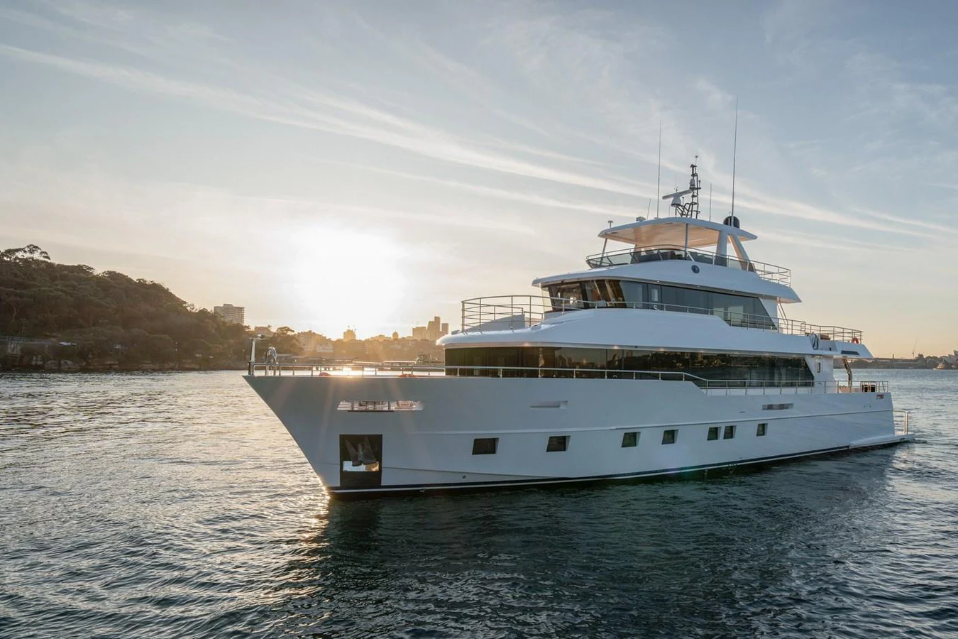 A sleek and modern yacht glides gracefully on the water at sunset. aboard NOMAD 101 ON-ORDER Yacht for Sale