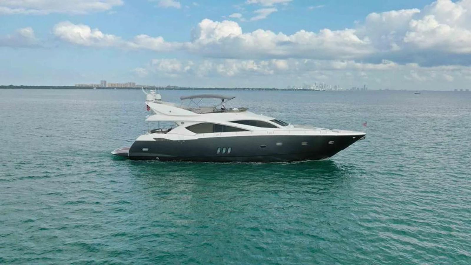A sleek and modern yacht cruising on calm waters under a partly cloudy sky. aboard 2006 SUNSEEKER MANHATTAN 'FINS UP' Yacht for Sale