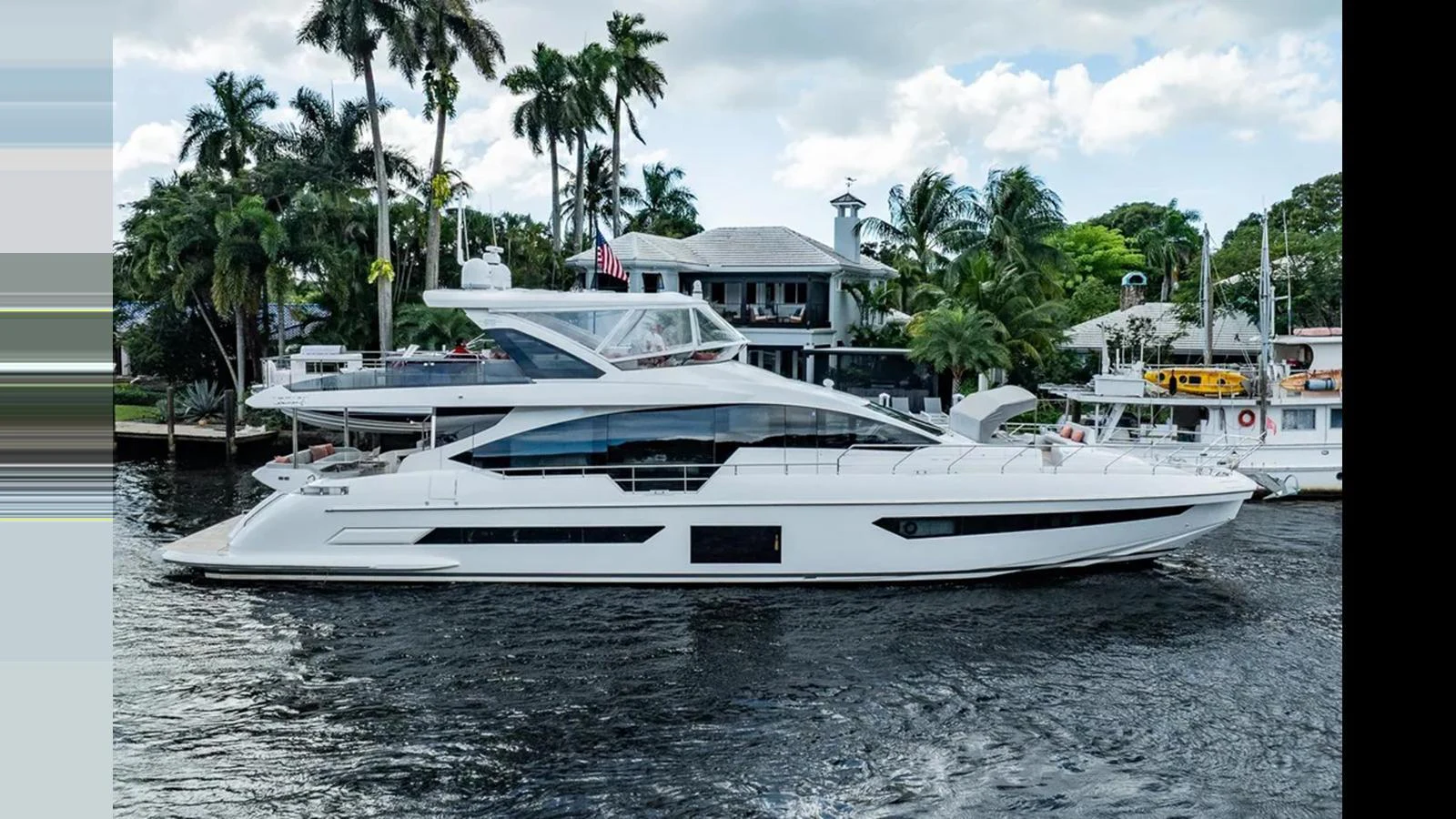 A sleek, modern yacht cruising along a waterfront lined with palm trees and luxurious homes. aboard 2022 AZIMUT GRANDE 25 METRI Yacht for Sale