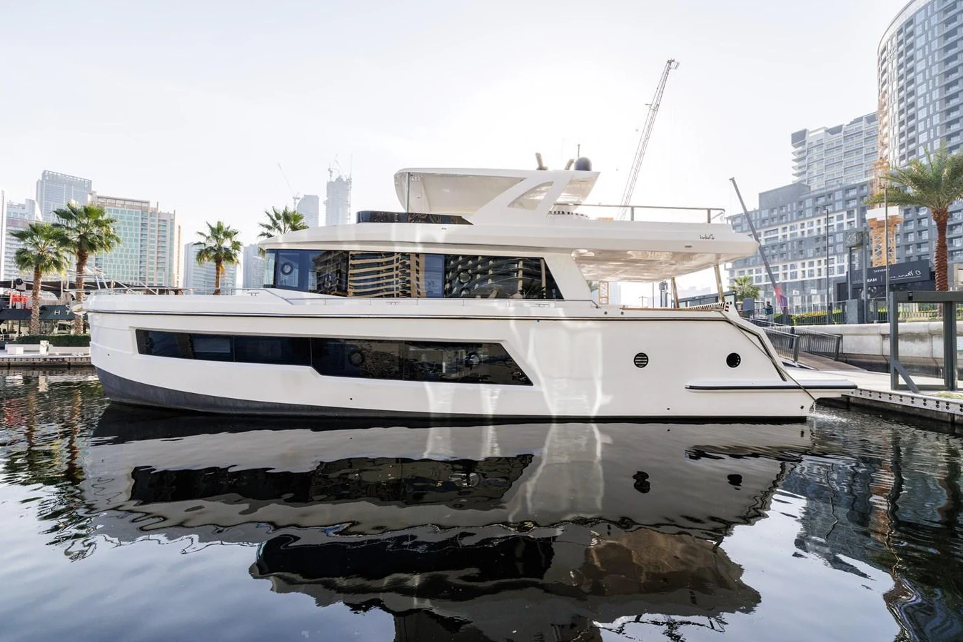 A sleek, modern yacht is docked in a marina with a cityscape in the background. aboard AL SULTAN Yacht for Sale