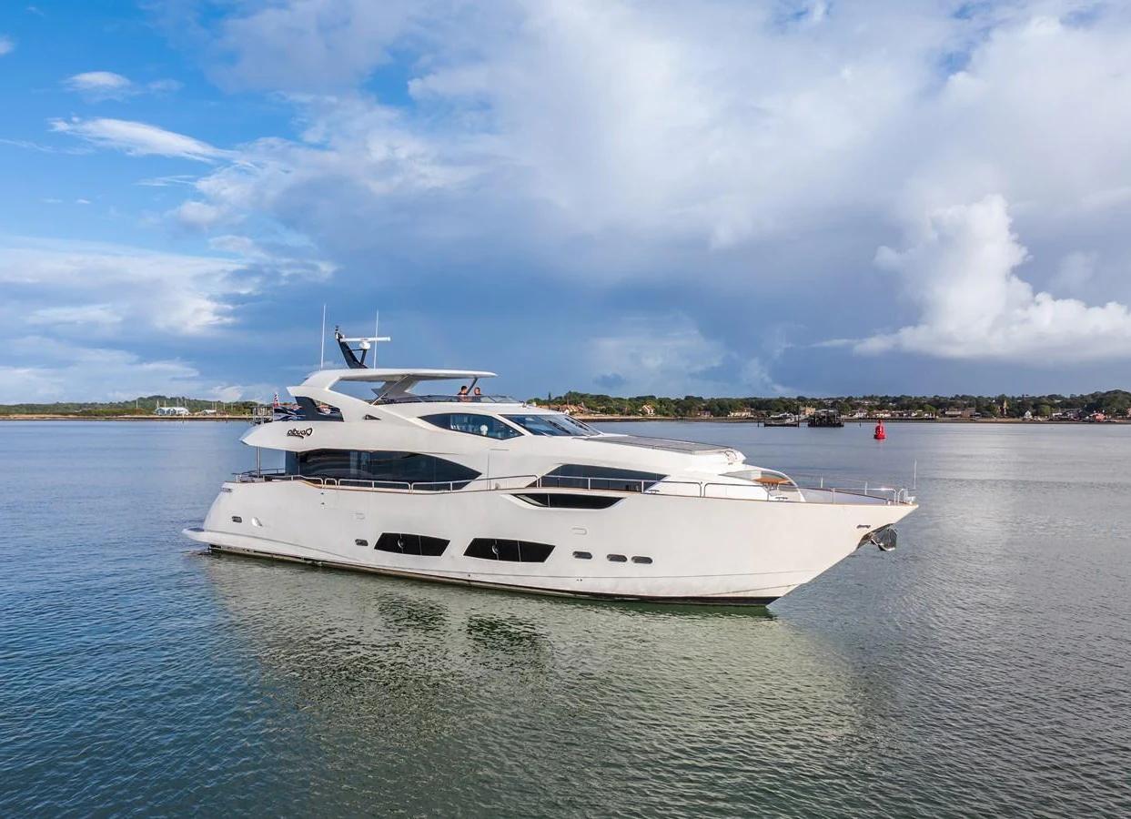 A sleek and modern yacht glides gracefully on calm waters under a partly cloudy sky. aboard CLOUDIA Yacht for Sale