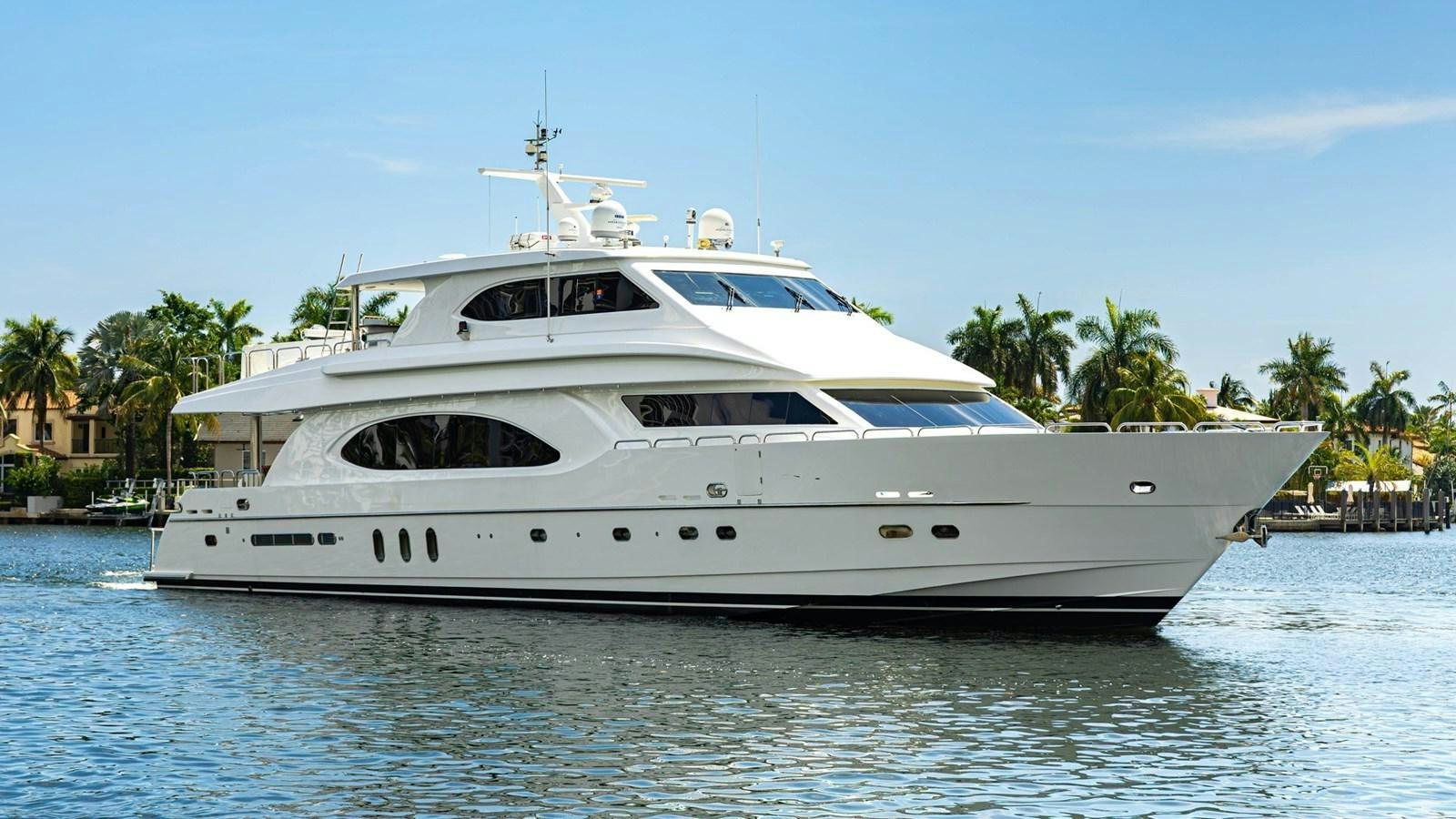 A luxurious yacht glides gracefully on calm waters with a backdrop of palm trees and clear skies. aboard MY ANGEL Yacht for Sale