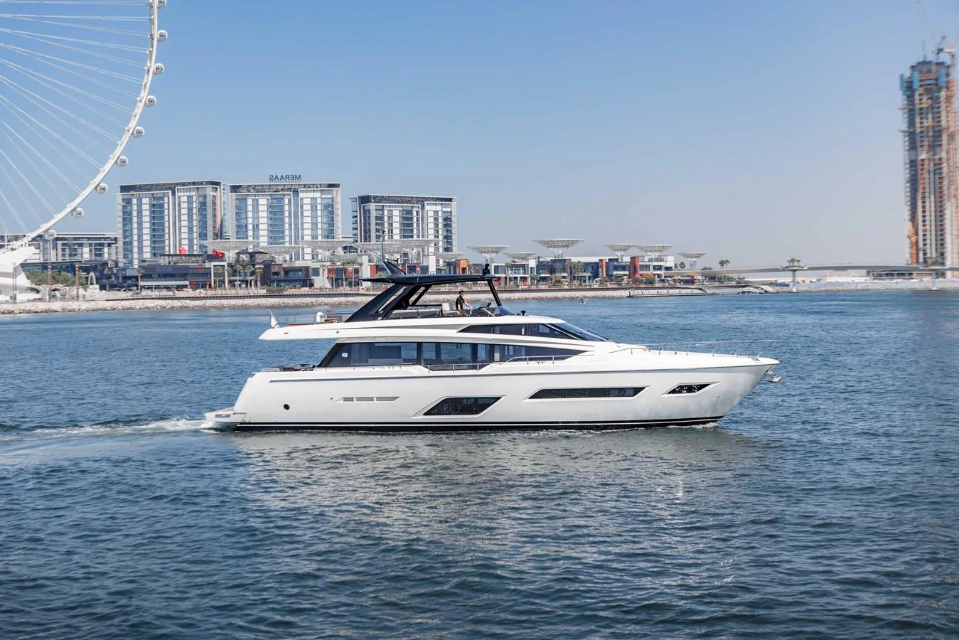 A sleek and modern yacht cruises gracefully on calm waters with a cityscape in the background. aboard BELLA III Yacht for Sale