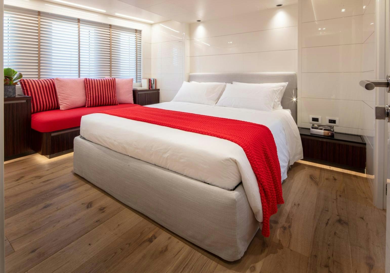 a bed with red pillows aboard ATOM Yacht for Sale