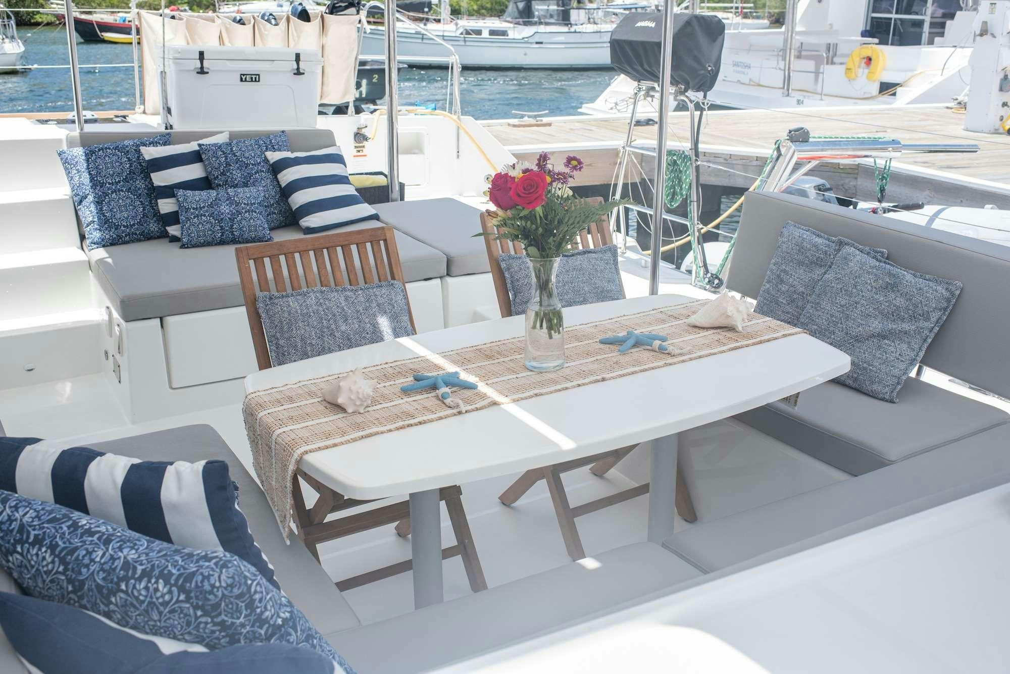 a table with chairs and a couch on a deck aboard TIME OUT Yacht for Charter