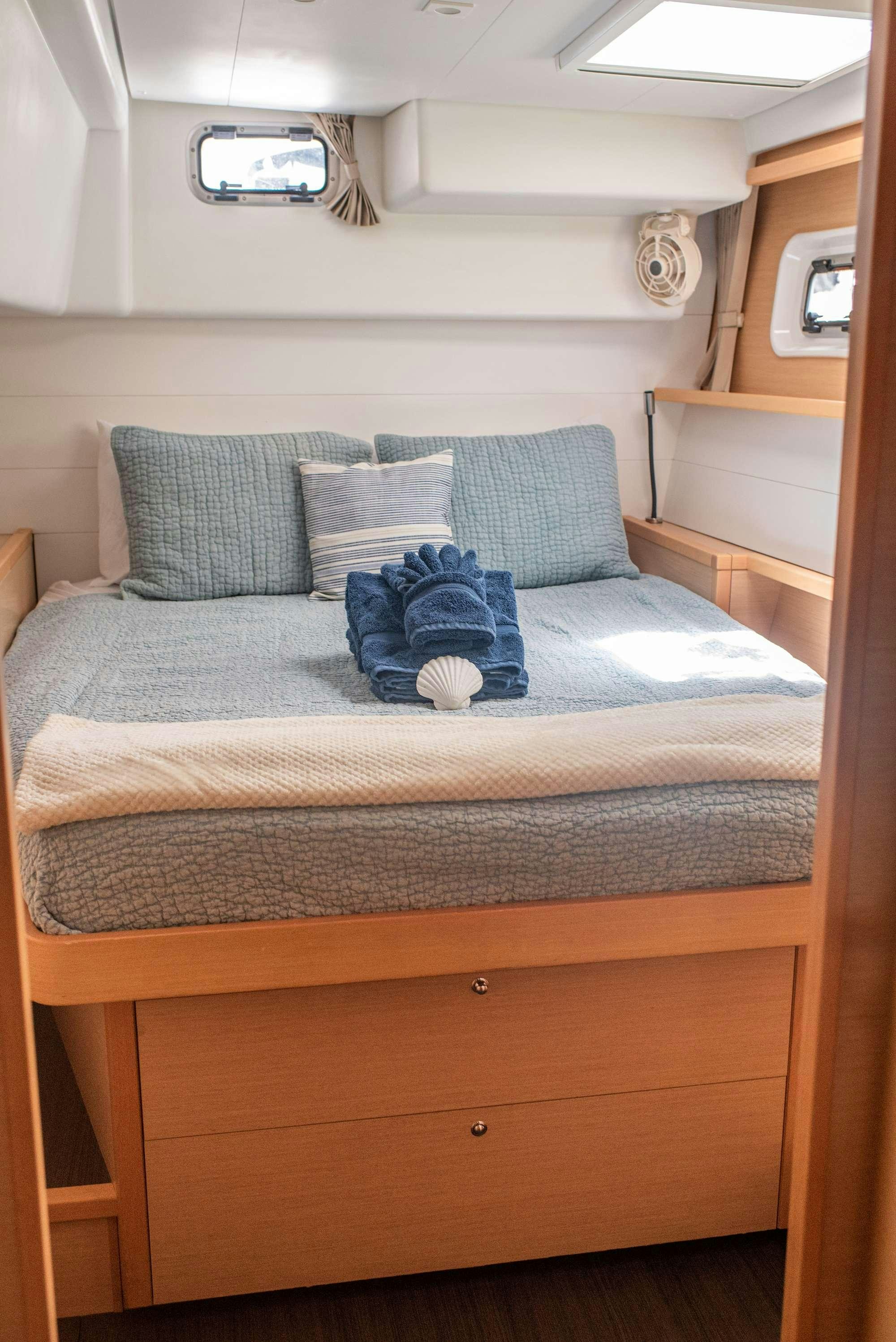 a bed with blue pillows aboard TIME OUT Yacht for Charter