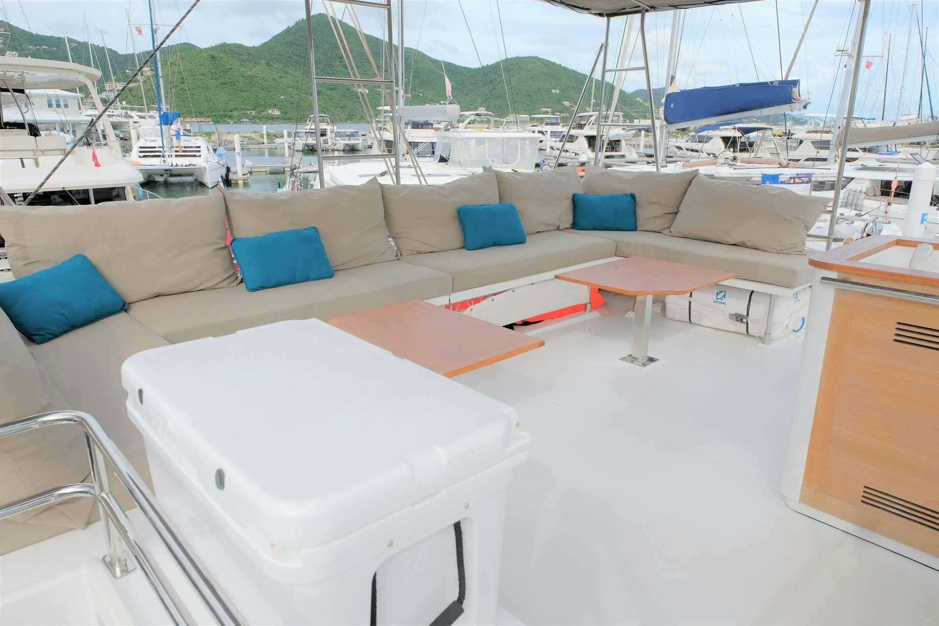 a room with a couch and a table with a boat in the background aboard PORT TO VINO Yacht for Charter