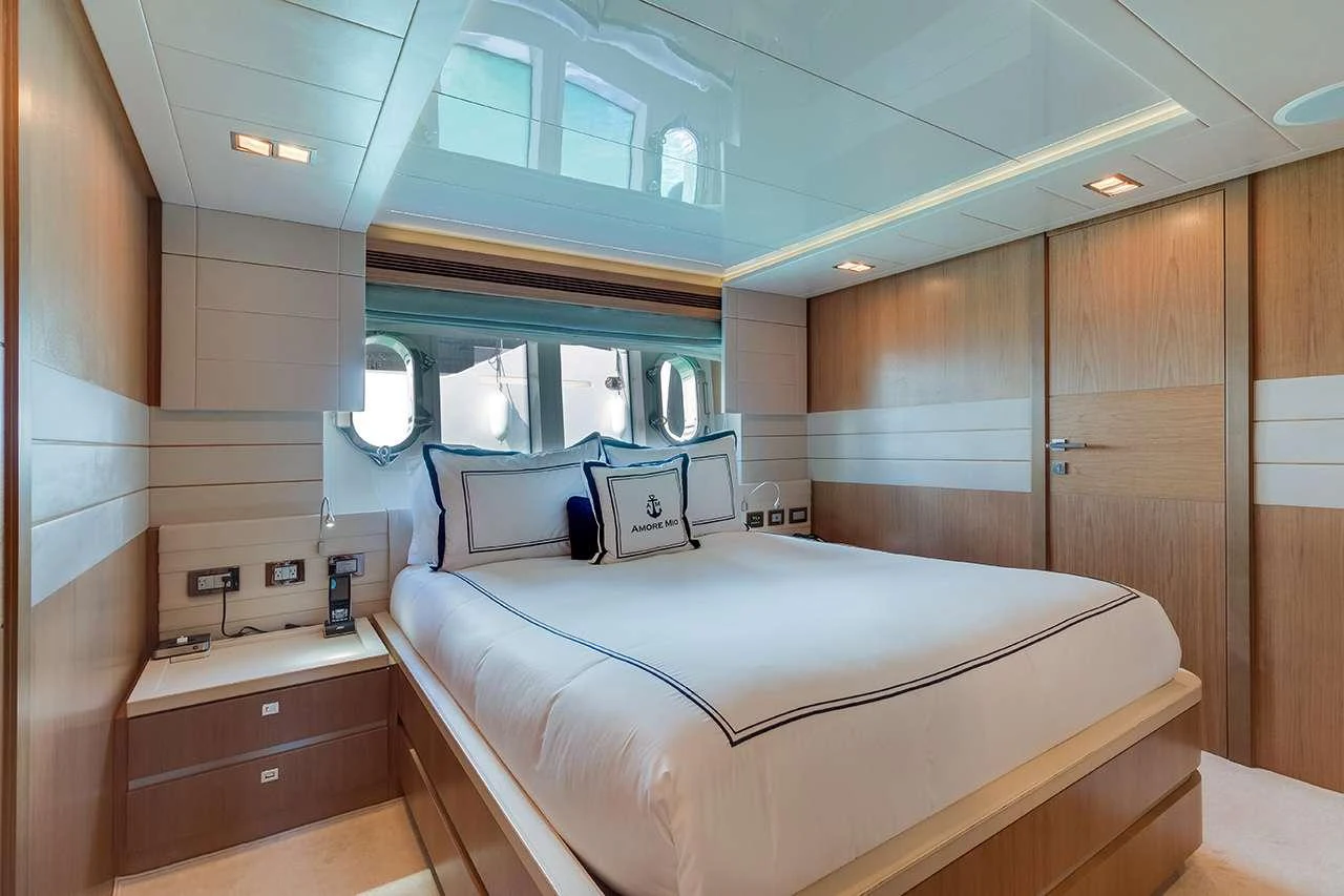 The stateroom features a luxurious bed with elegant bedding and ample natural light from the windows. aboard LA MAR Yacht for Charter