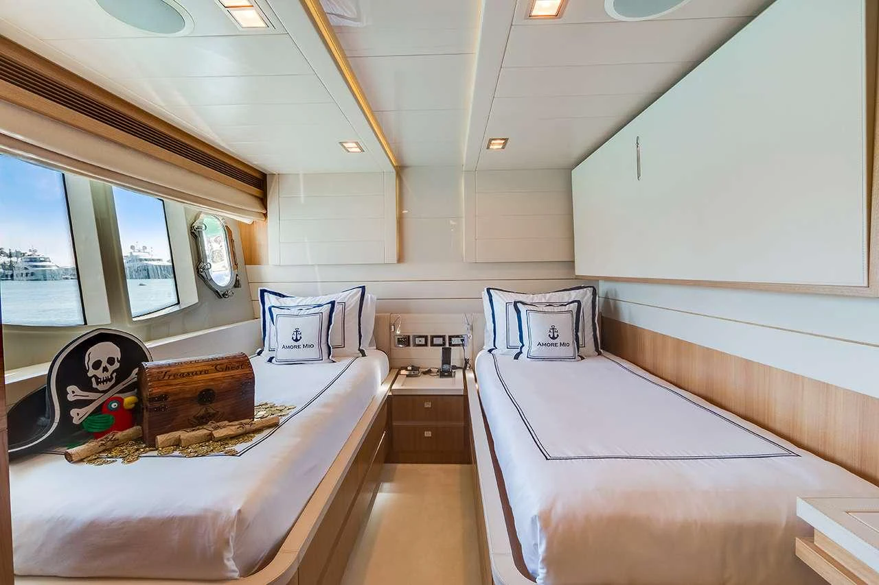 The guest stateroom features two single beds with nautical-themed decor and ample natural light. aboard LA MAR Yacht for Charter