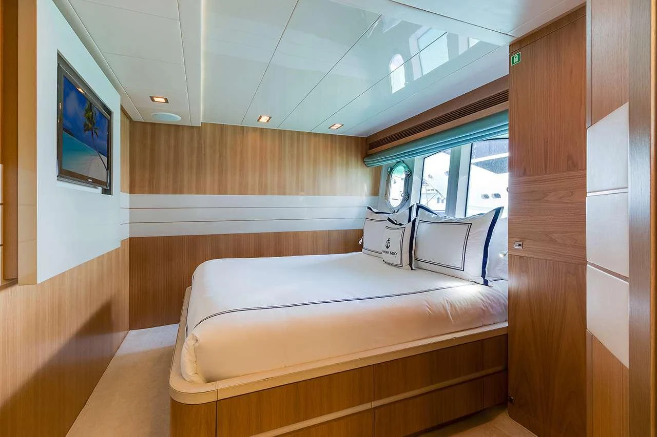 The stateroom features a plush bed with elegant bedding and ample natural light from large windows. aboard LA MAR Yacht for Charter