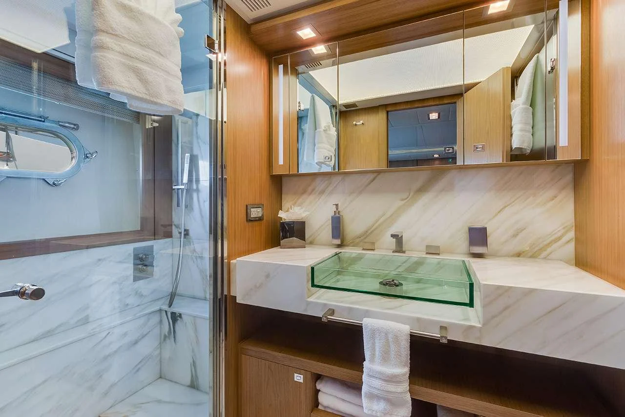 The yacht's bathroom features a modern design with a glass sink and marble accents. aboard LA MAR Yacht for Charter