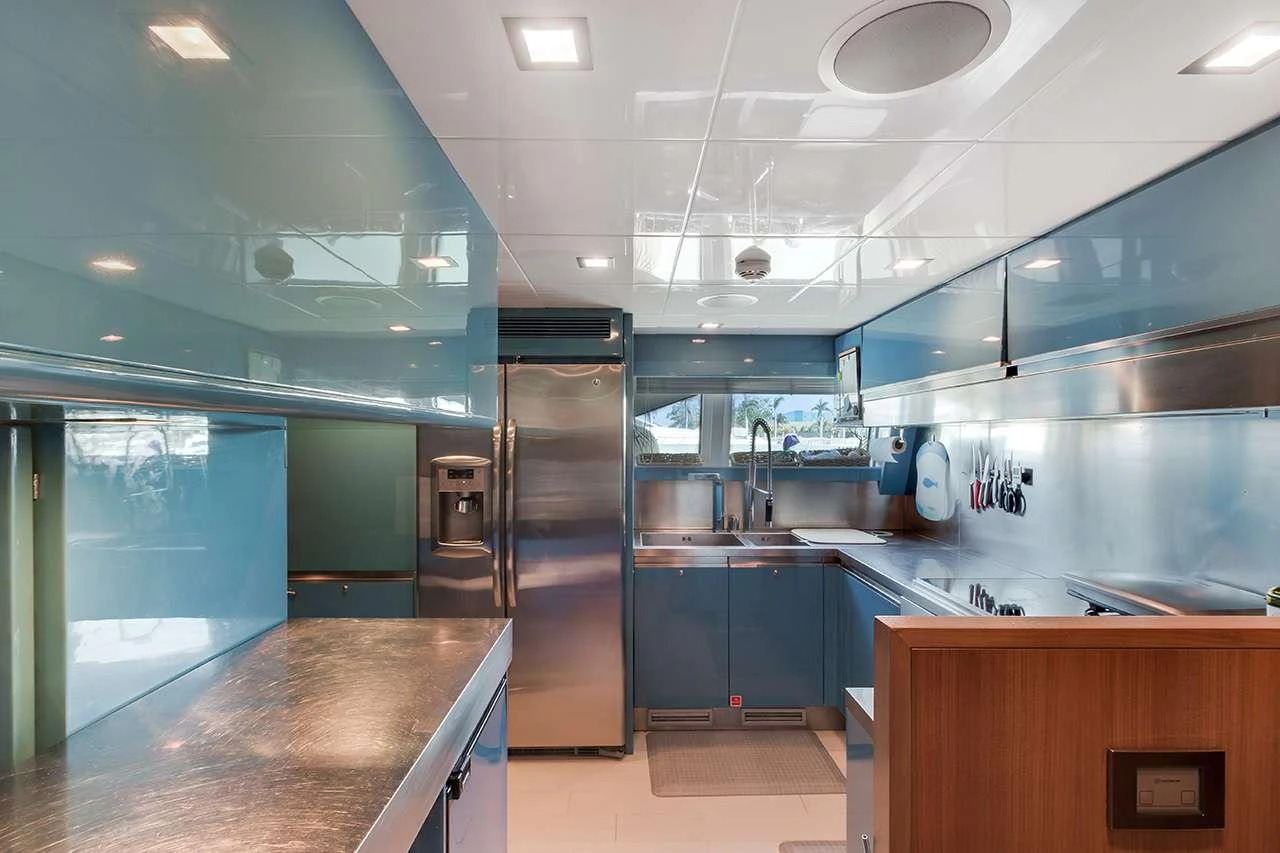 The yacht's galley features sleek blue cabinetry and modern stainless steel appliances. aboard LA MAR Yacht for Charter