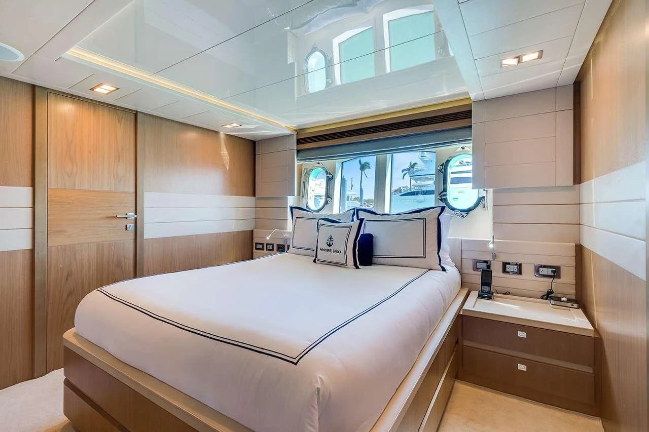 The stateroom features a luxurious bed with elegant bedding and ample natural light from the windows. aboard LA MAR Yacht for Charter