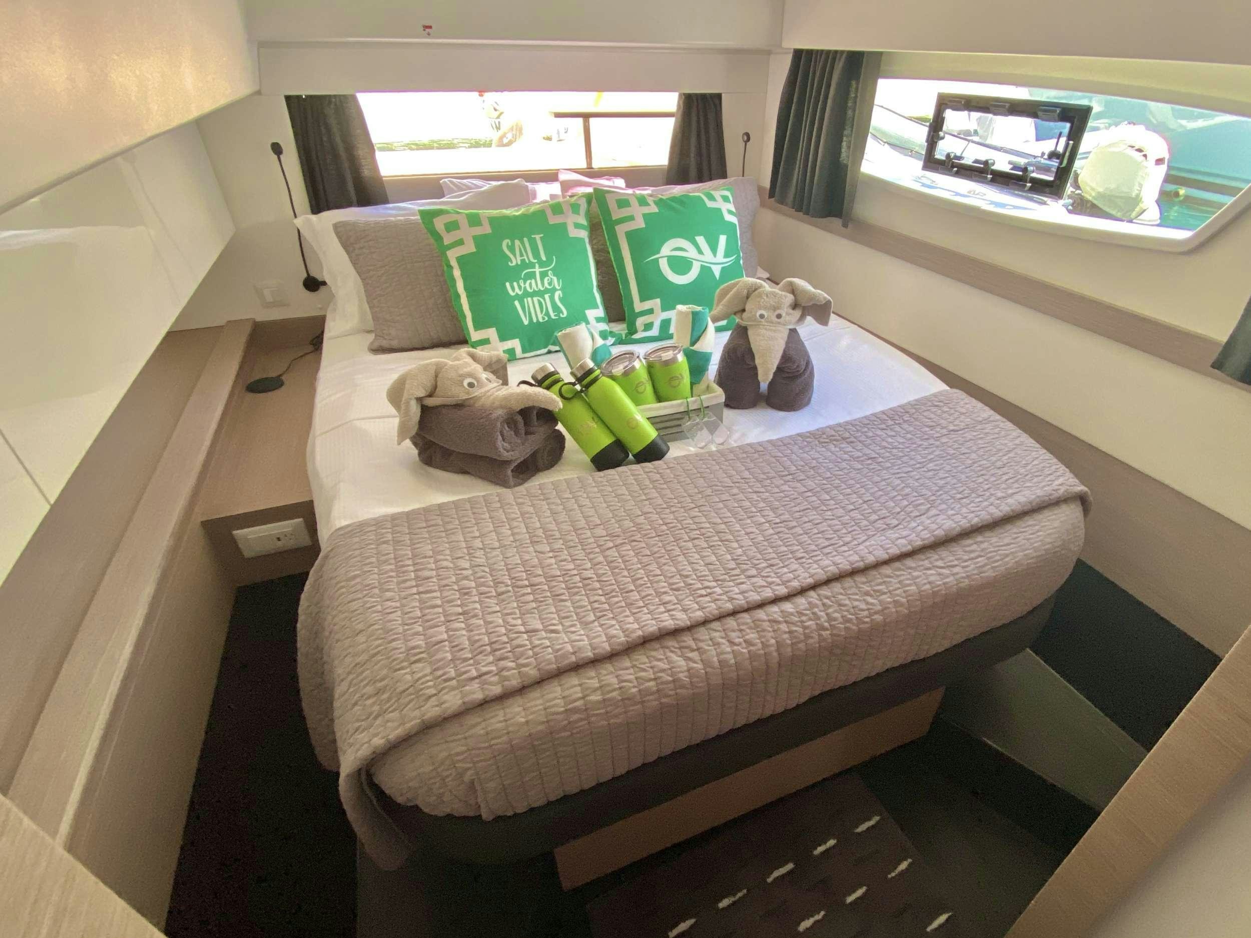 a bed with a green and white pillow and a green box on it aboard O.V. Yacht for Charter
