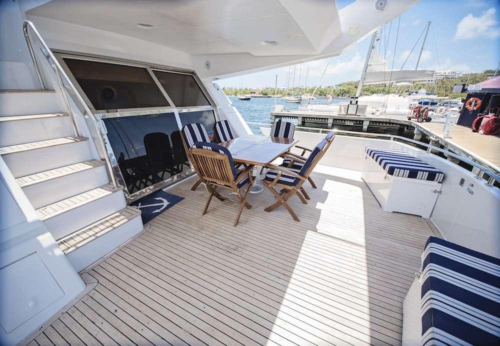 a deck with a table and chairs on it aboard COOL BREEZE 65 Yacht for Charter