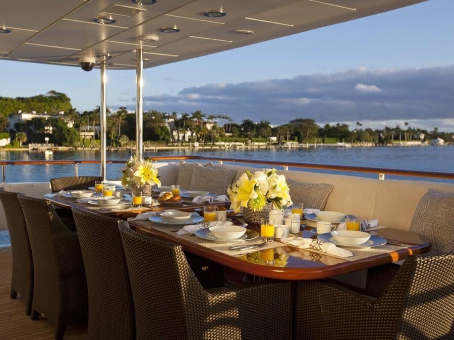 a table set for a meal on a deck overlooking a body of water aboard LEVERAGE Yacht for Charter