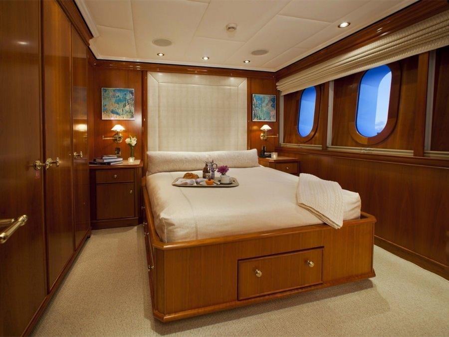 a bedroom with a bed and a window aboard LEVERAGE Yacht for Charter