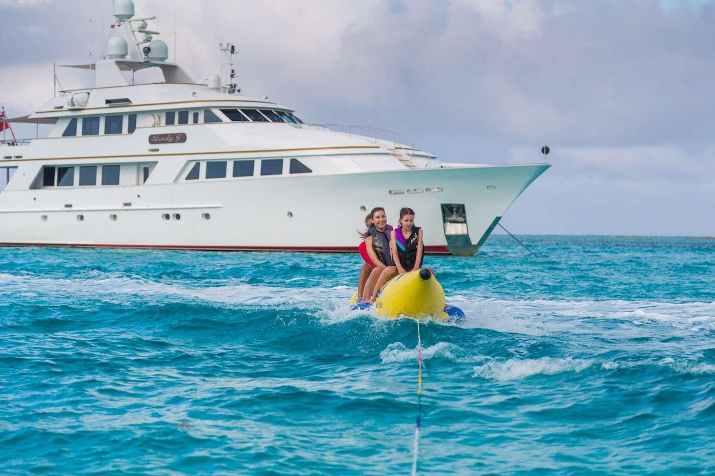 two people on a yellow raft in the water by a large white boat aboard LADY J Yacht for Charter