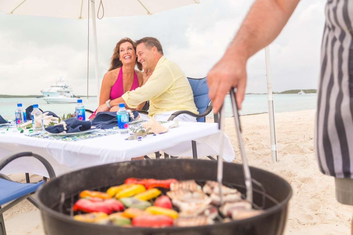 a man and woman cooking on a grill aboard LADY J Yacht for Charter