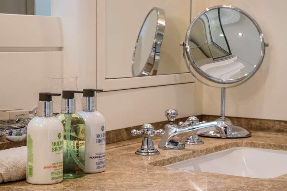 a bathroom sink with a large round mirror aboard PURA VIDA Yacht for Charter