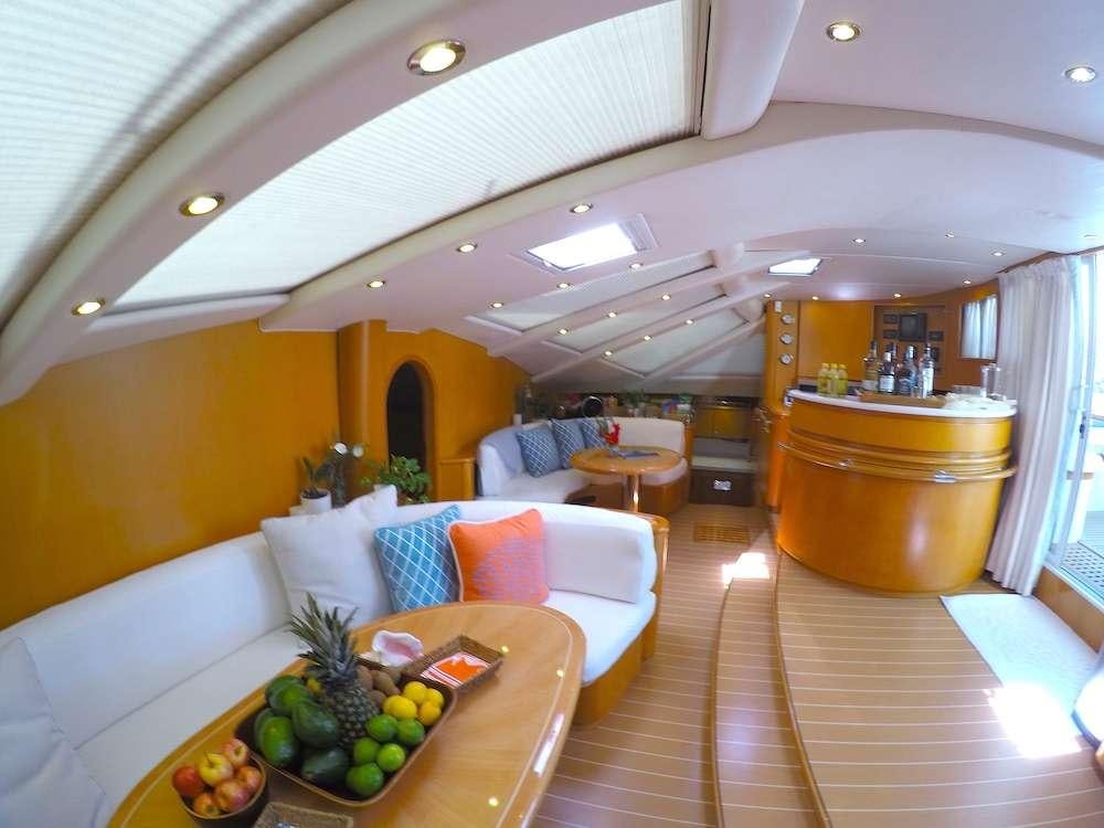 a large living room with a large wood table and a large pot of fruit on the table aboard KELEA Yacht for Charter