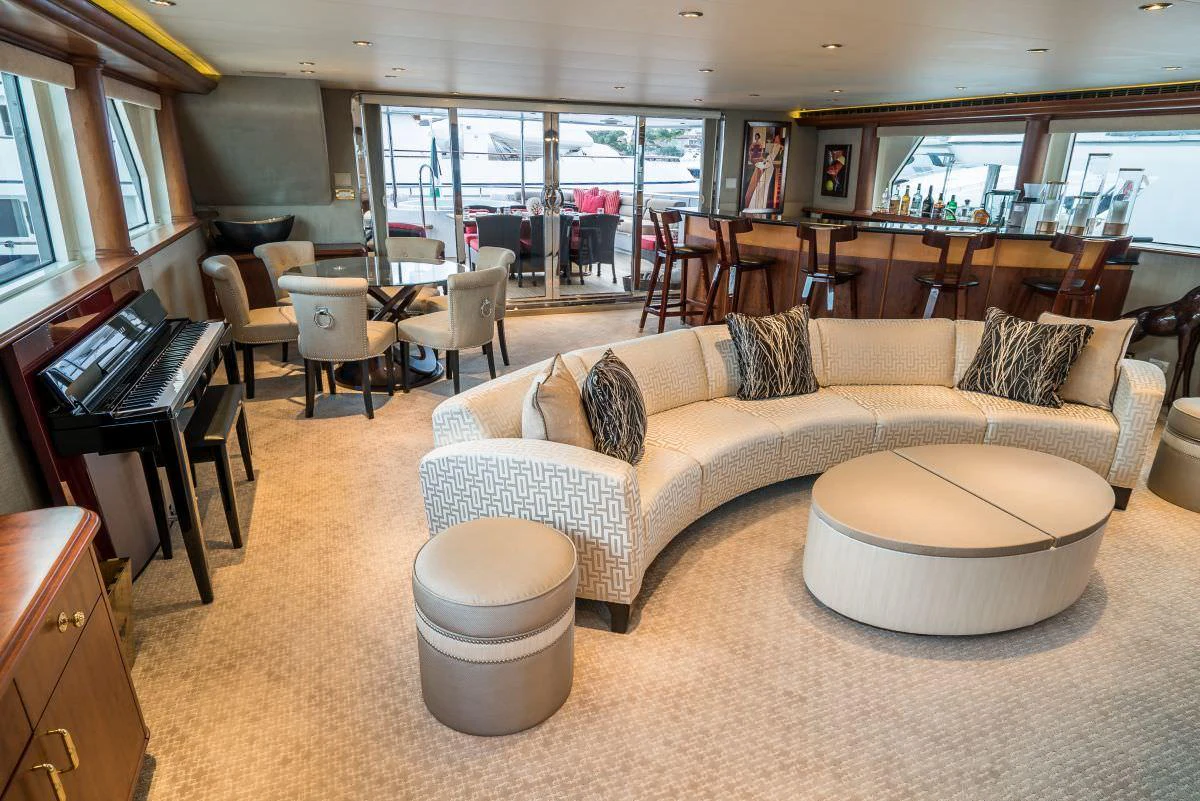 The spacious salon features a curved sofa, a piano, and a bar area, creating a luxurious and inviting atmosphere. aboard CHARLOTTE ANN Yacht for Charter