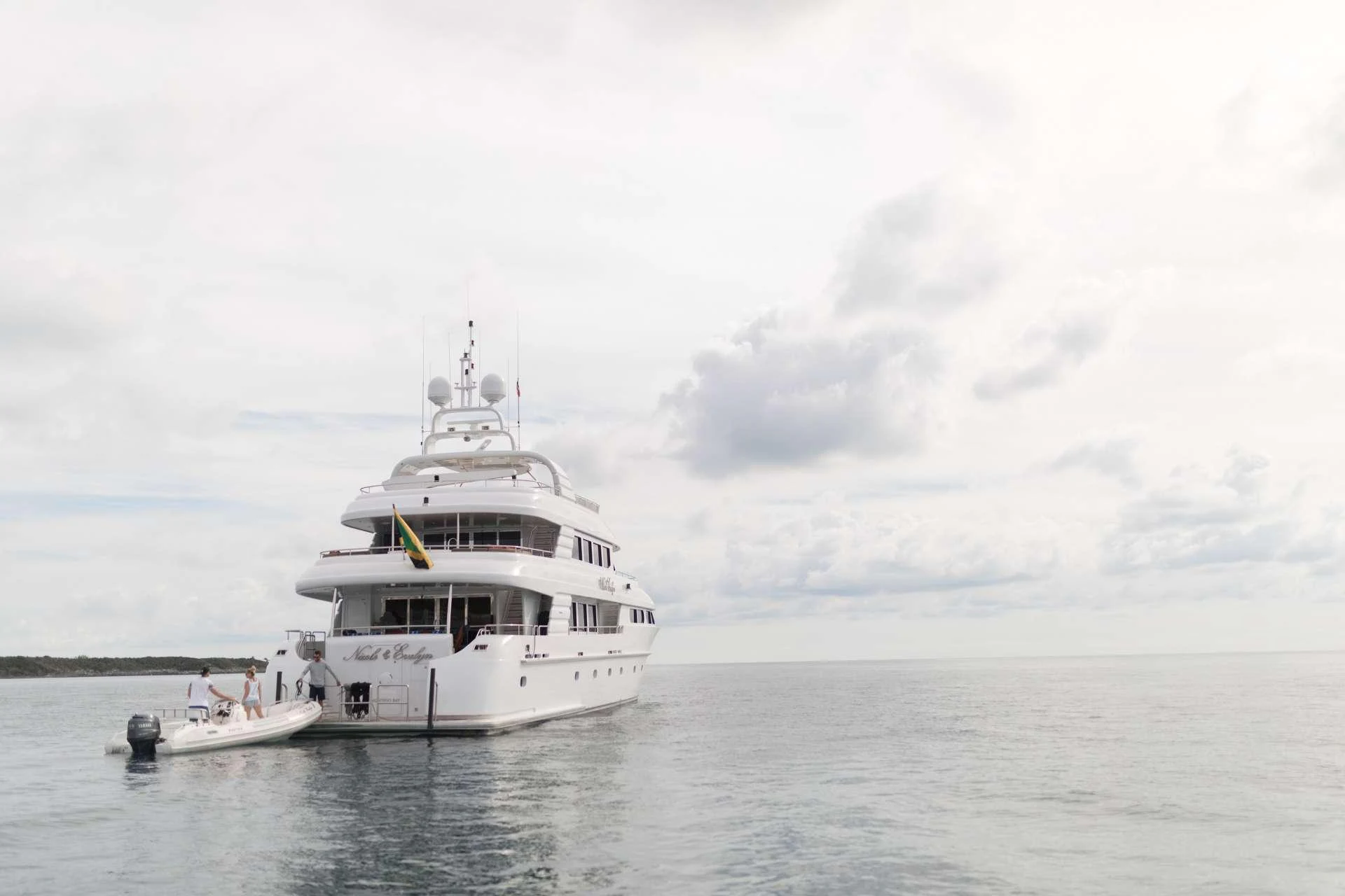 A luxurious yacht is anchored in calm waters under a cloudy sky. aboard CHARLOTTE ANN Yacht for Charter