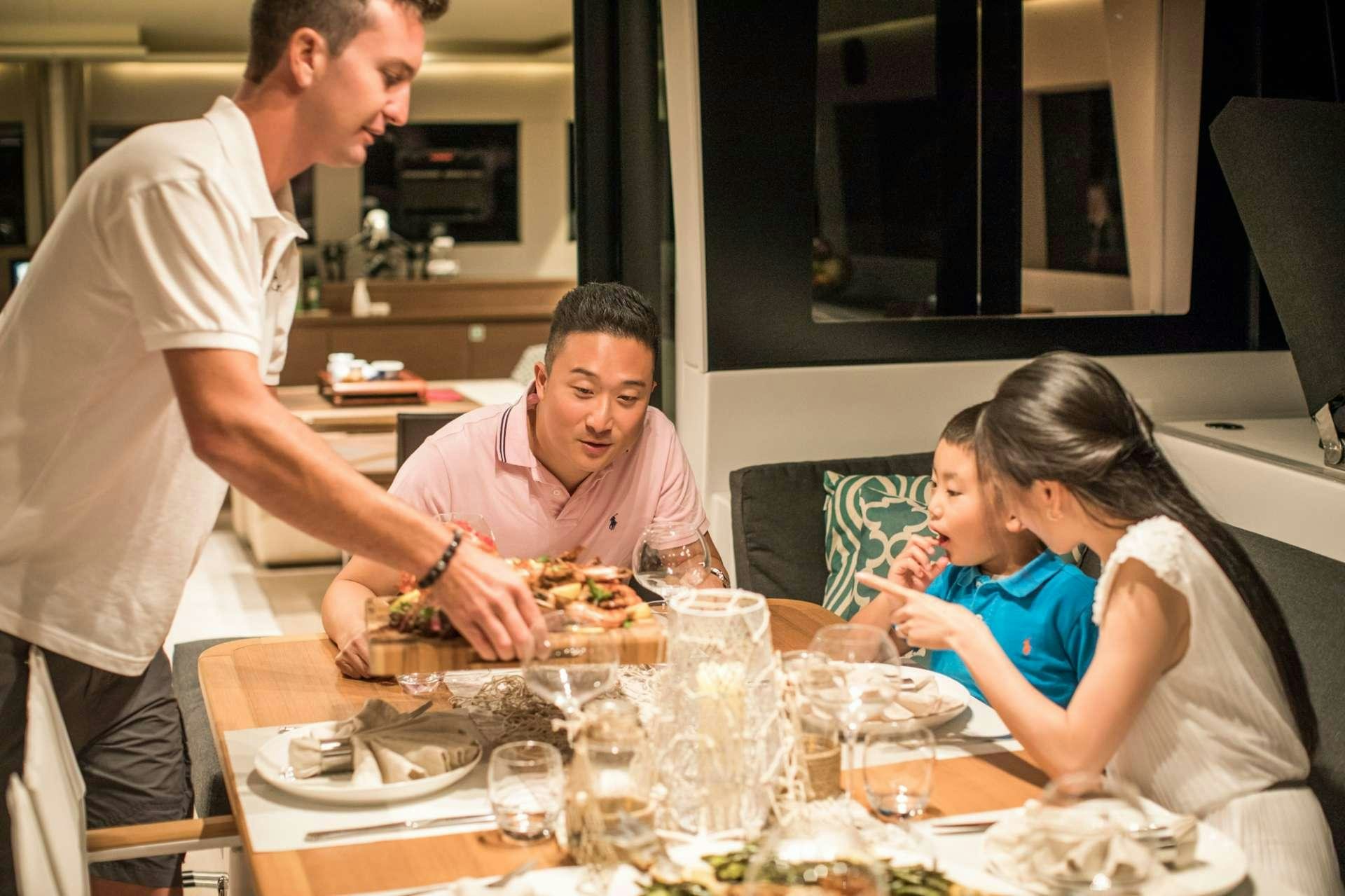 a group of people sitting around a table with food aboard LADY FIONA Yacht for Charter