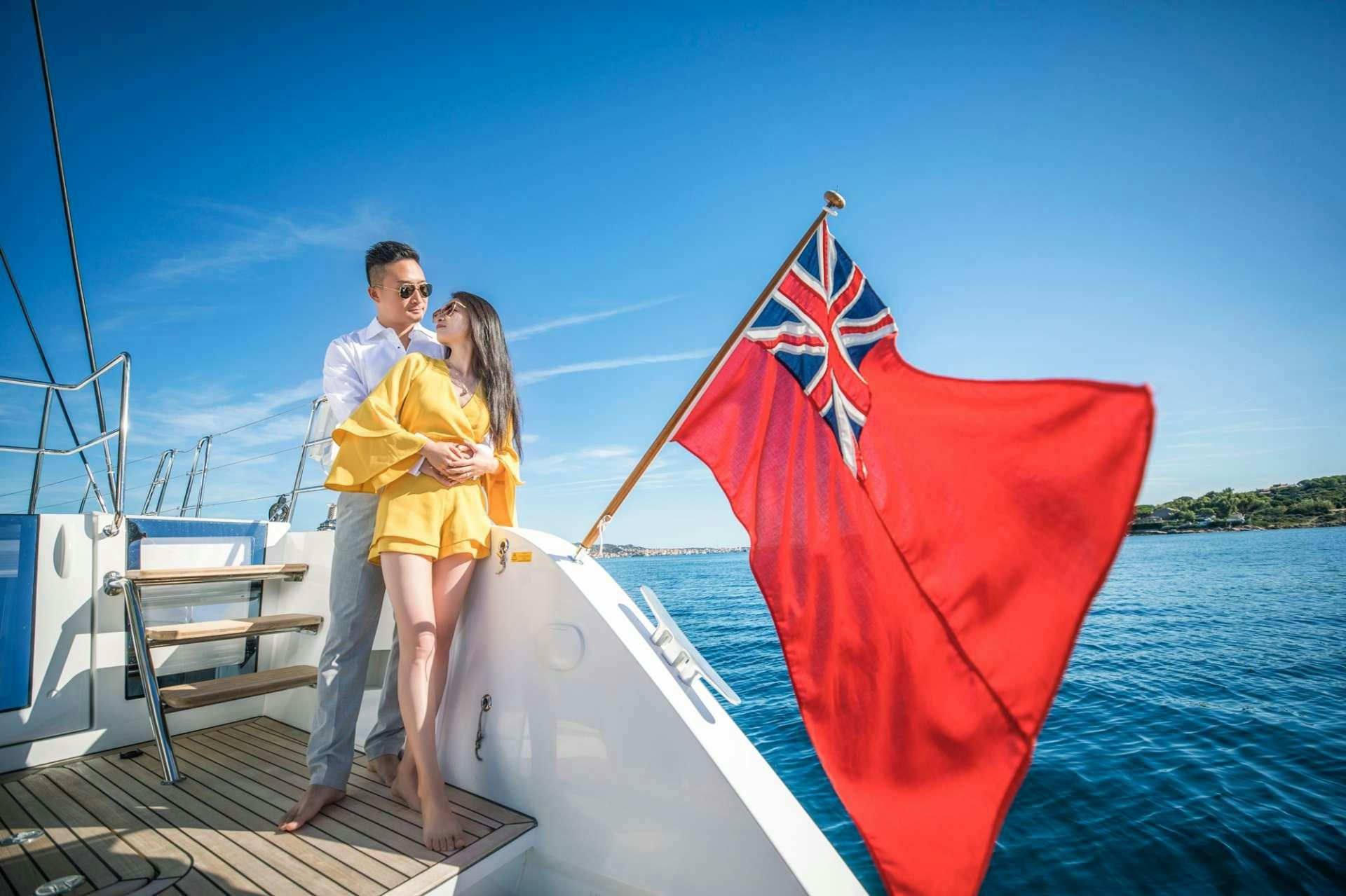a man and woman posing on a boat with a flag aboard LADY FIONA Yacht for Charter