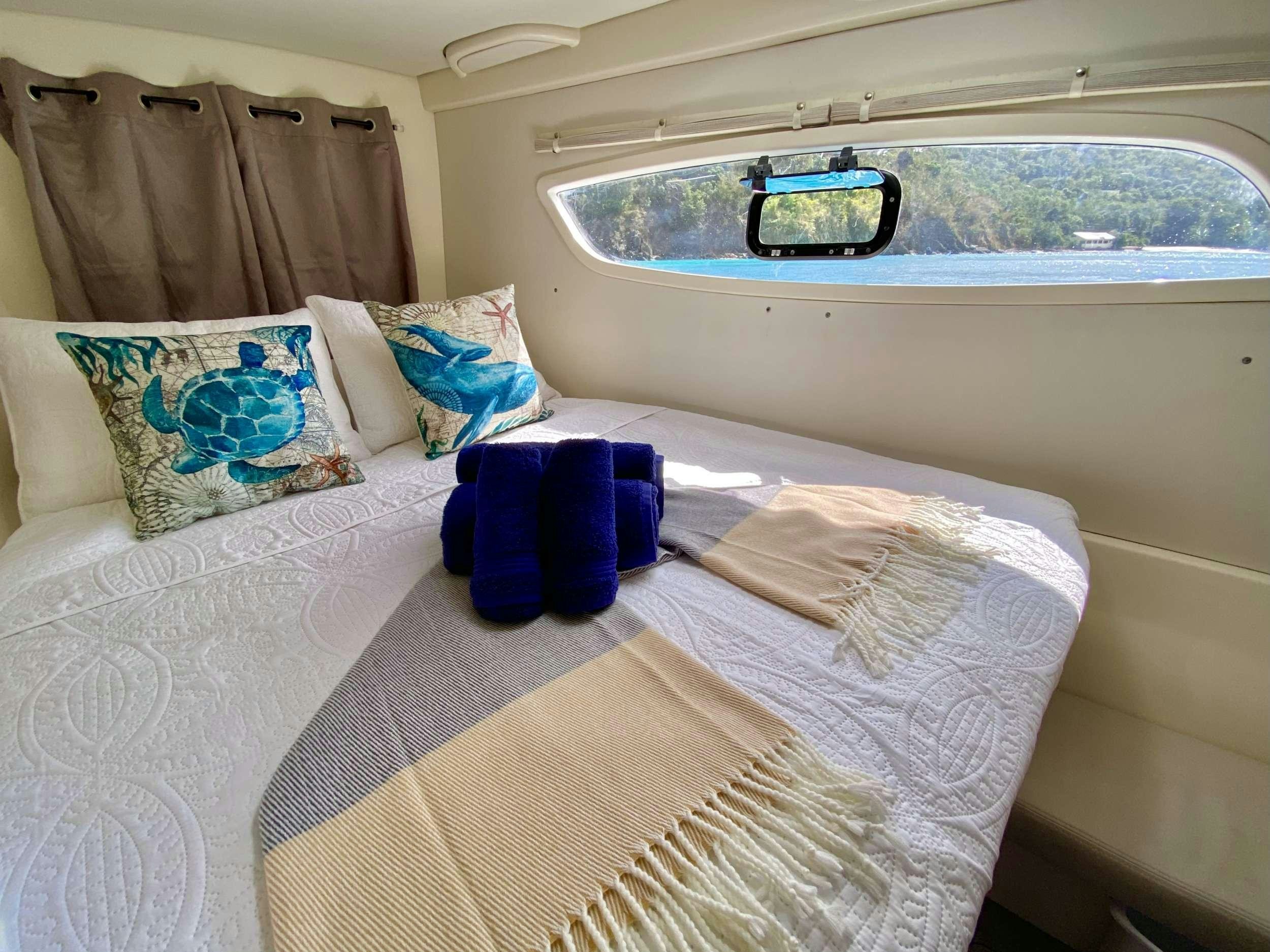 a bed with a blue and white blanket and blue socks on it aboard LET'S PLAY TWO Yacht for Charter