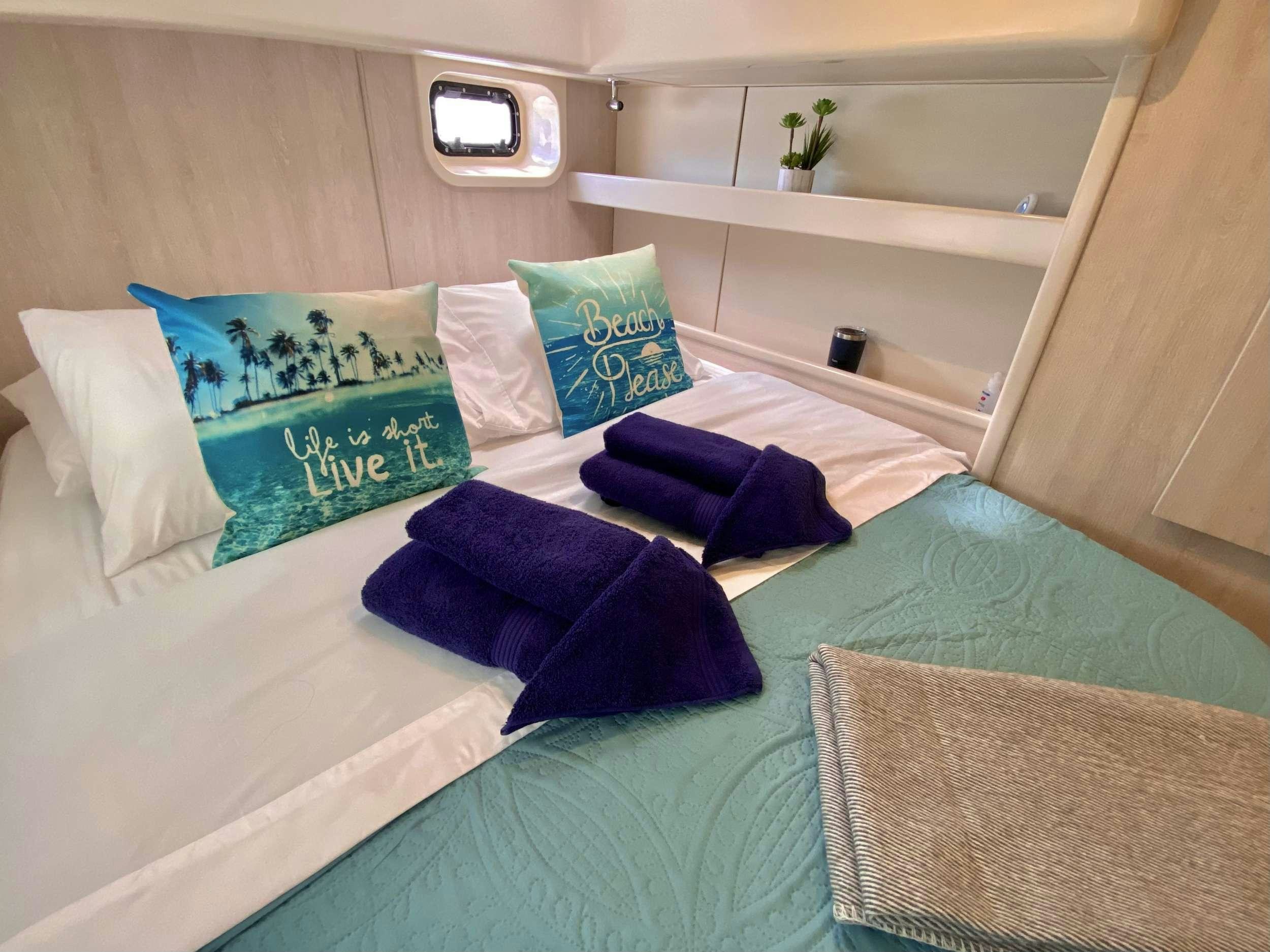 a bed with blue pillows aboard LET'S PLAY TWO Yacht for Charter
