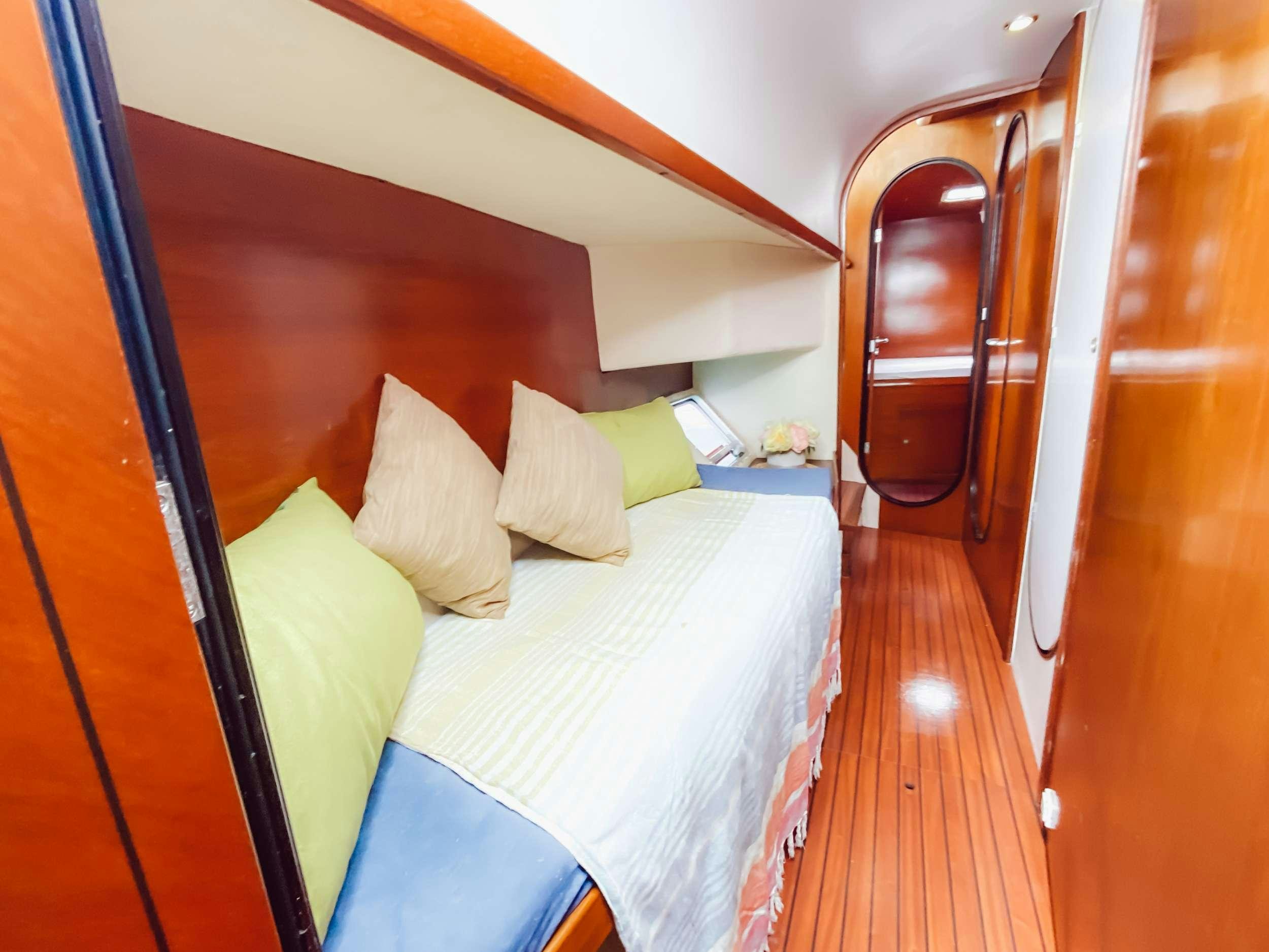 a bed with a white sheet and a wooden door aboard Cataja Yacht for Charter