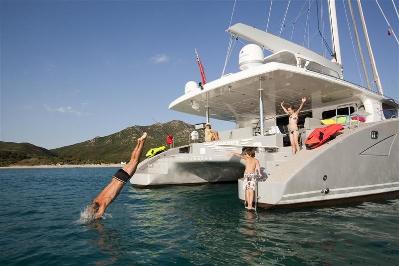 a couple of people jumping out of a boat aboard MAVERICK Yacht for Charter
